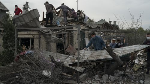 I volontari lavorano per rimuovere le macerie in un sito in cui diverse case sono state distrutte dopo un attacco russo in una zona residenziale di Zaporizhia, in Ucraina.