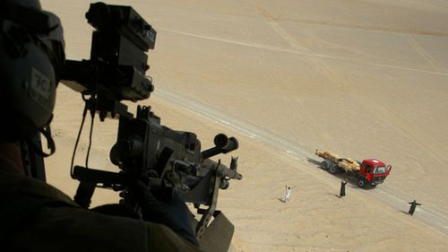 A RAF loadmaster in a Puma helicopter trains his machine gun on a truck in southern Iraq, 30 March 2003.