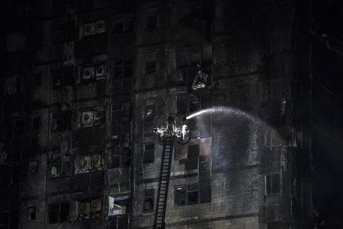 A firefighter douses the  Abbco Tower in Sharjah, after a huge blaze ripped through the building.