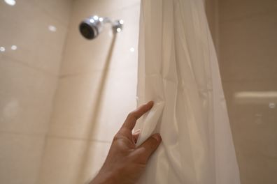 Person touching shower curtain. 