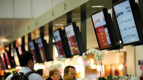 Qantas passengers check in at Sydney International Airport in Sydney. (AAP)