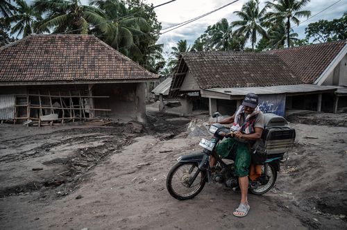 A man rides a bike past damaged homes at Sumber Wuluh village in Lumajang after the Mount Semeru volcano erupted in Indonesia
