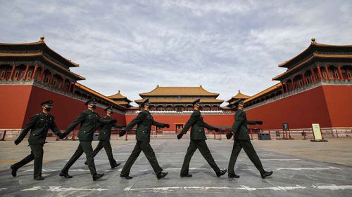 Masked soldiers march past the Forbidden City in Beijing.