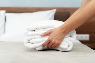 Maid with fresh clean towels during housekeeping in a hotel room