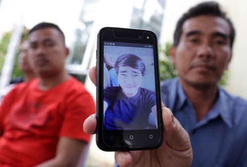 Abdul Rahman, 49, shows a picture of his son Riyan Aryandi, one of the plane crash victims, as relatives wait for the news  from forensic experts.