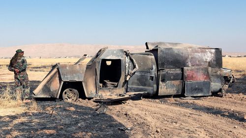 A Peshmerga soldier inspects burnt truck which was used by Islamic State militants after a heavy clashes with Iraqi forces. (AAP)