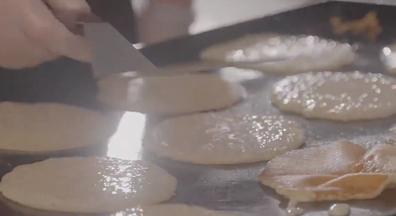 Close-up of a griddle with pancakes cooking.