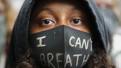 A girl wears a face mask during a Black Lives Matter rally in Parliament Square, in London, Saturday, June 6, 2020