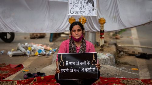 Tina Verma, 27, a social activist, holds a placard which reads, "Hang the killers of 9-year old child".