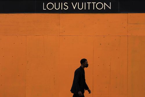 A man walks past a boarded-up window at a Louis Vuitton store in San Francisco, Sunday, Nov. 1, 2020, ahead of Election Day. (AP Photo/Jeff Chiu)