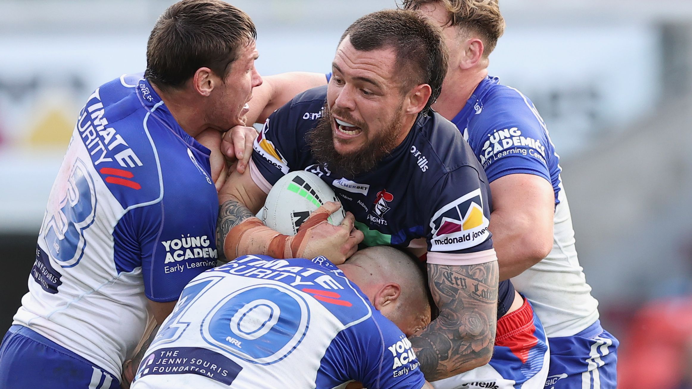 David Klemmer of the Knights is tackled by Bulldogs players.