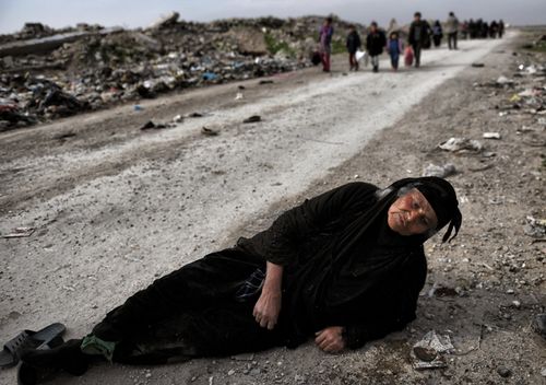 An Iraqi woman lies on the ground as civilians flee Mosul while Iraqi forces advance inside the city during fighting against Islamic State group's fighters on March 8, 2017 (AFP)