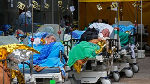 Patients lie on hospital beds waiting at a temporary holding area outside the Caritas Medical Centre in Hong Kong. 