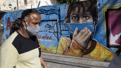 A man walks past a mural referencing the COVID-19 pandemic, painted in honour of health workers in Rio de Janeiro, Brazil, Thursday, May 21, 2020. The mural is by graffiti artist Angelo Campos, 39, who has lost two relatives to the new coronavirus. (AP Photo/Silvia Izquierdo)