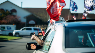 A Trump supporter gives a thumbs up as he's yelled at by residents while driving with a Trump Train Rally through the Regency Club Apartments which also serves as a polling precinct on Election Day in Warren, Mich., Tuesday, Nov. 3, 2020. (AP Photo/David Goldman)