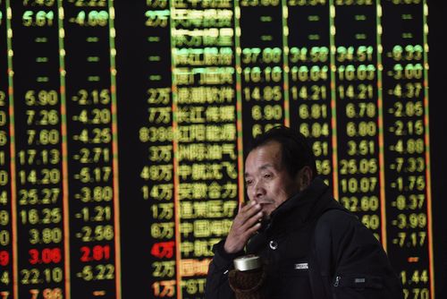 A Chinese investor walks past a display showing stock prices at a brokerage house in Hangzhou in eastern China's Zhejiang province. (AAP)