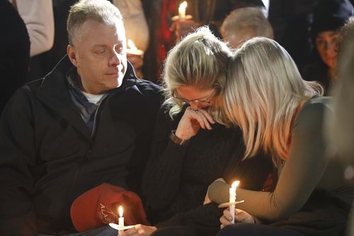 Family members console one another at the Mohawk Gatway Bridge in the city of Amsterdam during a candlelight vigil for the 20 people who were killed