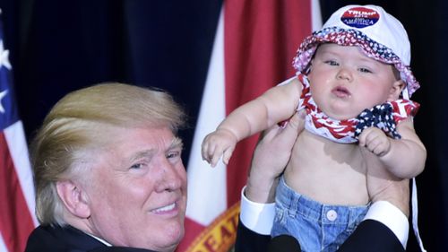 Donald Trump holds a baby on the campaign trail. (AFP)