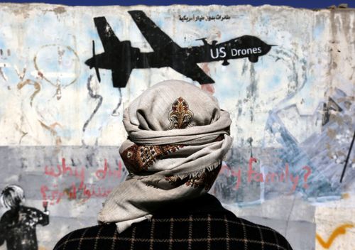 A Yemeni stands in front of graffiti protesting US drone operations in war-affected Yemen.
