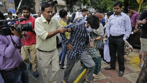 Indian national, Puneet Puneet, centre, accused of driving drunk in a hit-and-run car accident that killed an Australian student in Melbourne in 2008, is helped by his parents as they come out after being produced at a court in New Delhi in 2015. (AAP)