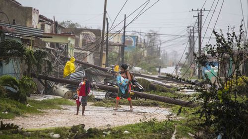 Residents walk near downed power lines felled by Hurricane Irma in Caibarien. (AAP)