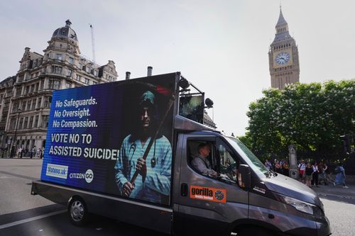 Demonstrators for assisted dying hold banners outside Parliament in London, Friday, June 20, 2025