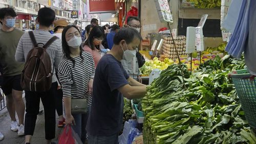 People wearing face masks shop at a local produce market in Hong Kong.