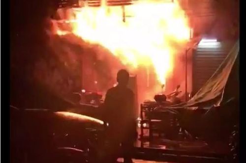 A Chinese firefighter sprays water to distinguish the fire in an arson attack of a KTV bar. (AAP)