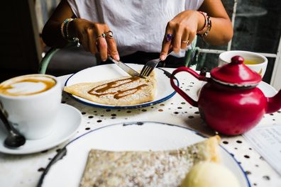 unrecognizable woman eating a crepe in a vintage coffee shop in the city