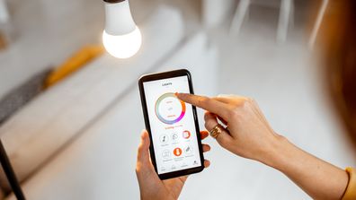 Woman adjusting a smart light bulb with her phone