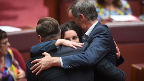 Jacqui Lambie receives a hug by Australian Greens Senators Nick McKim and Peter Whish-Wilson (Image: Facebook)