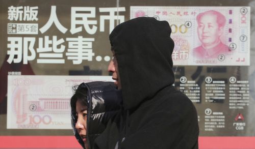 Residents walk past board highlighting the security markers on the latest Yuan note