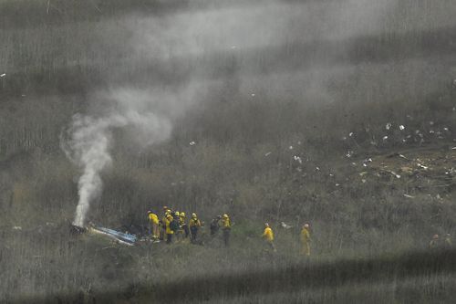 Firefighters work at the scene of a helicopter crash that killed former NBA basketball player Kobe Bryant, his 13-year-old daughter and seven other people on board.