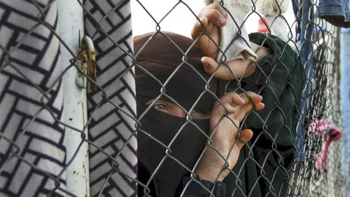 Woman clings to the wire fence surrounding the Al Hawl camp in Northern Syria.