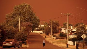 A woman looks down her street as the sky turns red from the fires on January 04, 2020 in Bruthen Australia. Evacuations Continue Across East Gippsland As State Of Disaster Is Declared