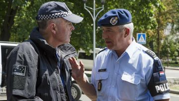 A Dutch, right, and Australian policemen talk in the city of Donetsk, eastern Ukraine, where they are being kept as heavy fighting surrounds the MH17 crash site.