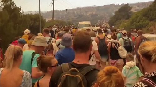 Crowds wait to be evacuated as wildfires burn in this video screengrab obtained from social media, in Rhodes, Greece, July 22, 2023.