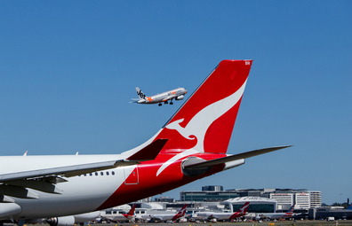 Qantas aircraft on tarmac and Jetstar plane flying in the background