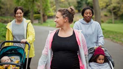 Two mums with kids in strollers and a pregnant woman walking.