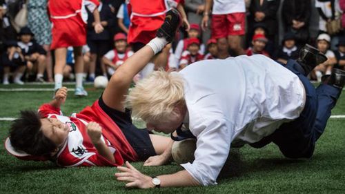 Boris Johnson crunched a young Japanese boy with a shoulder charge during a rugby photo op.