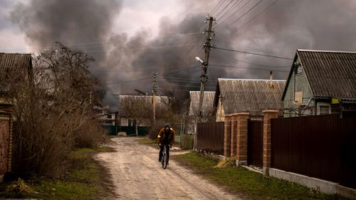 A man rides his bicycle near a factory and a store which have been hit by a Russian bombardment of Irpin, on the outskirts of Kyiv.