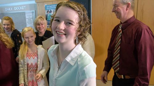 Deserae Turner smiles outside the courtroom surrounded by her family, following Jayzon Decker's sentencing hearing Wednesday, Feb. 7, 2018, in Logan, Utah. Decker, a teenage boy convicted in a plot that left Deserae Turner with a gunshot wound to the head will serve at least 15 years and up to life in prison. (Eli Lucero/Herald Journal, via AP, Pool)