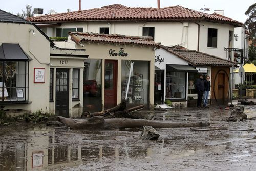 Debris and mud cover the street in front of local area shops after heavy rain brought flash flooding. (AAP)