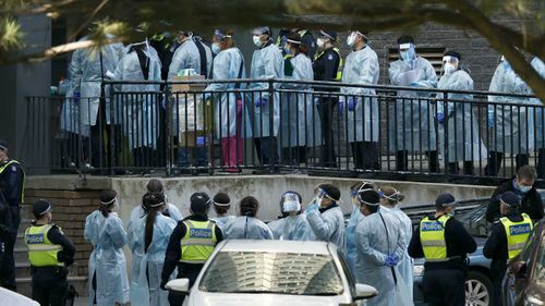 Lines of health care professionals are seen entering the North Melbourne Public Housing tower complex.