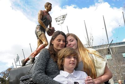 The Stynes family pose in front of a statue of Jim. (AAP)