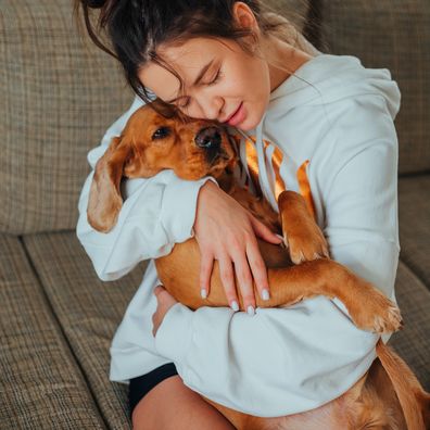 Stock photo of a woman cuddling a dog.
