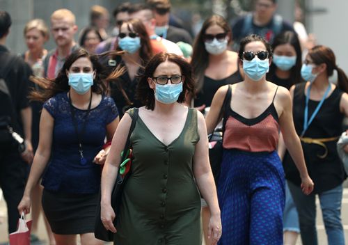 People wear face masks to protect from smoke haze as they cross a busy city street  in Sydney, Australia. Smoke haze continues to hang over the city as bushfires burn across New South Wales. 