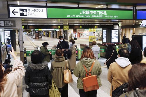 People gather in front of a ticket gate at a station as train services are suspended following an earthquake in Sendai, Miyagi prefecture, Japan Saturday, March 20, 2021