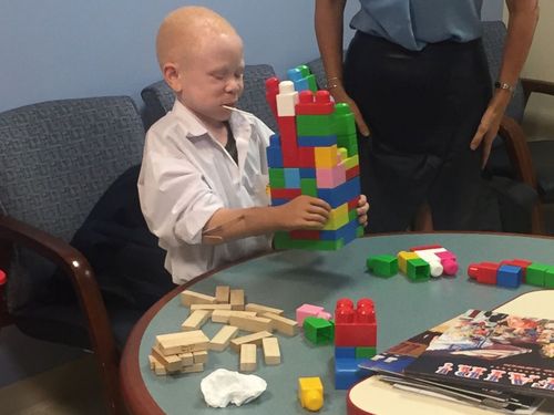 Baraka, 7, uses his new prosthetic to stack blocks. (Image: ABC News America)