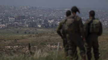 Israeli soldiers look at destroyed buildings in the Gaza Strip as they stand near the Israeli-Gaza border, as seen from southern Israel, Tuesday, April 9, 2024.  
